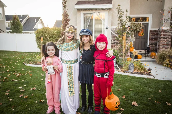 ハロウィンの衣装を着た子供たちのグループは 10月に装飾された近所で屋外でトリックや治療を行っています — ストック写真