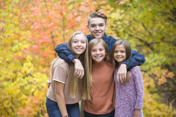 Beautiful Portrait of smiling happy teen kids outdoors. Four siblings standing together for a cute picture on a warm fall day