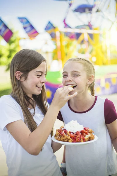 屋外のカーニバルや遊園地で漏斗ケーキを食べる2人の笑いと笑顔の十代の女の子 この率直な写真の可愛い表情 — ストック写真