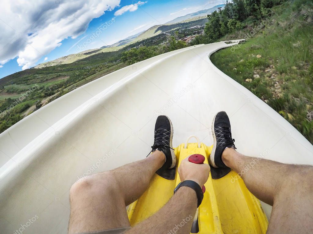 Point of view photo of a man riding down an downhill alpine slide on a fun summer vacation in the mountains