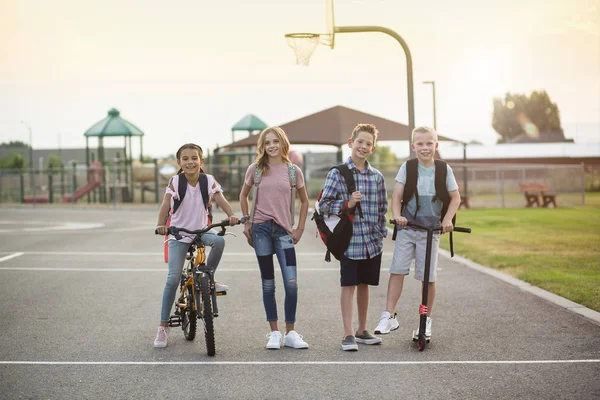 各种各样的学生一起聊天 一起从学校走回家 男孩和女孩骑自行车和摩托车离开学校大楼的全长照片 — 图库照片