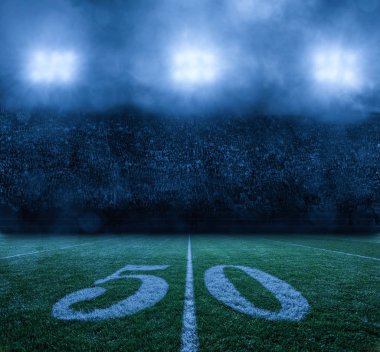Amerikan Futbol Stadyumu, 50 yarda çizgisinde. Bulutlu bir gecede stadyum ışıkları. Fotoğrafta kimse yok, sadece arka plan.