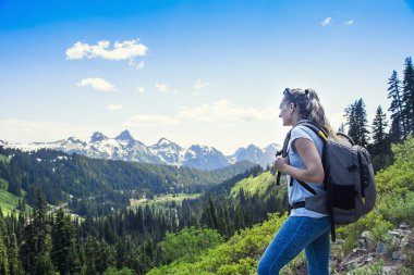 Washington 'daki Rainier Dağı Ulusal Parkı' nda güzel manzaralı bir dağ sırasının yakınında yürüyüş yapan bir kadın. Bir gün boyunca kar kaplı buzullara bakıyorum.