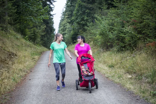 Two Women 30S Walking Talking Together Trail Pushing Baby Stroller — Stock Photo, Image