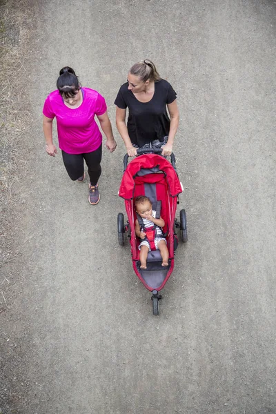 View Two Women 30S Walking Talking Together Trail Pushing Baby — Stock Photo, Image