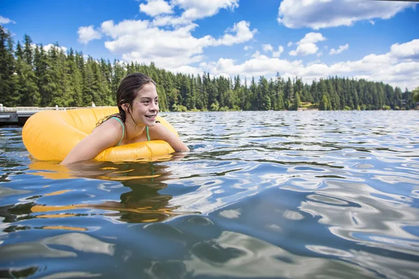 在一个温暖的夏日里 一个漂亮的少女在湖面玩耍的时候 在一个充气管子上漂浮着 — 图库照片