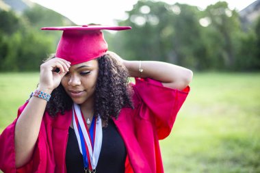 Çok ırklı güzel bir kadının samimi portresi mezuniyet kepi ve cübbesini giyiyor. Güzel yüzüne odaklan.