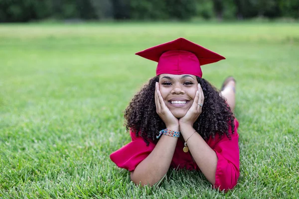 一个戴着毕业帽和婚纱的多民族美女的画像 当她躺在草地上的时候 她笑得很开心 — 图库照片