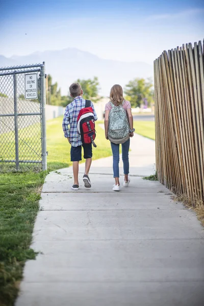 一緒に学校に歩いている2人の小学生の後ろからの眺め — ストック写真