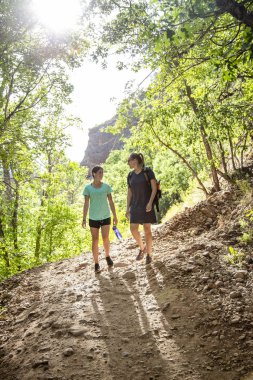 Bir yaz günü manzaralı bir dağ yolunda yürüyüş yapan iki kadın. Doğanın tadını çıkaran ve aktif olan insanların yaşam tarzı fotoğrafı.