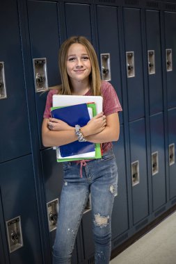 Okul koridorunda duran bir ortaokul öğrencisinin portresi. Güler yüzlü liseli kız gündüzleri kitap okuyor ve elinde tutuyor.