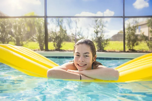 快乐的少女漂浮在室外游泳池里 一个惊慌失措的女孩的无忧无虑的 有趣的 快乐的画像 她笑着坐在充气的木筏上享受着一天的阳光 — 图库照片