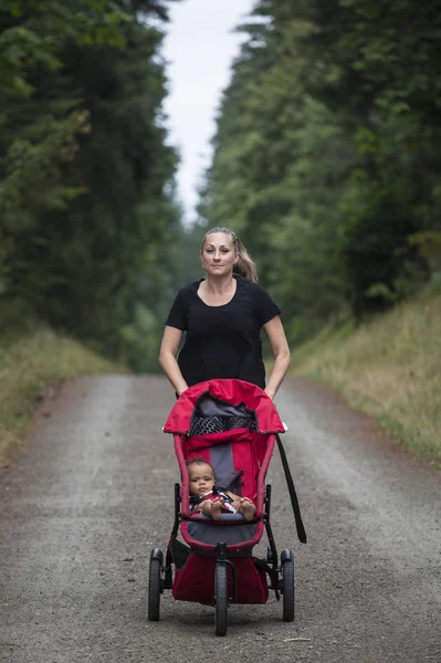 Aantrekkelijke Vrouw Die Een Pad Rent Haar Kinderwagen Buiten Duwt — Stockfoto