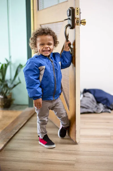 かわいい男の子は彼の家の前のドアを開ける 彼の顔に大きな笑顔で周りを見回す 2歳の男の子の遊び心のある楽しい写真 — ストック写真