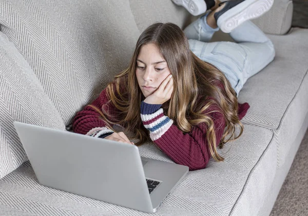 Entediado Adolescente Menina Estudando Casa Usando Laptop Deitado Sofá — Fotografia de Stock