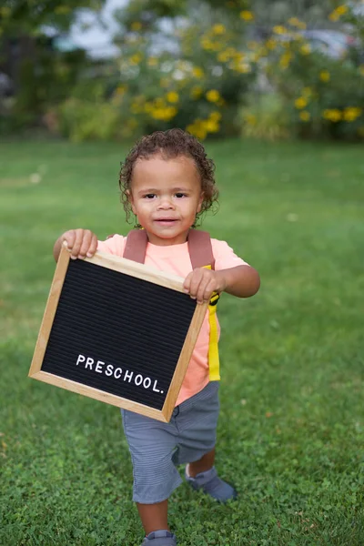 Bonito Menino Criança Pequena Com Mochila Grama Verde Segurando Placa — Fotografia de Stock