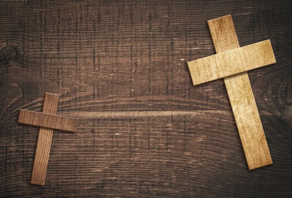Wooden cross on brown old tabletop or wall surface