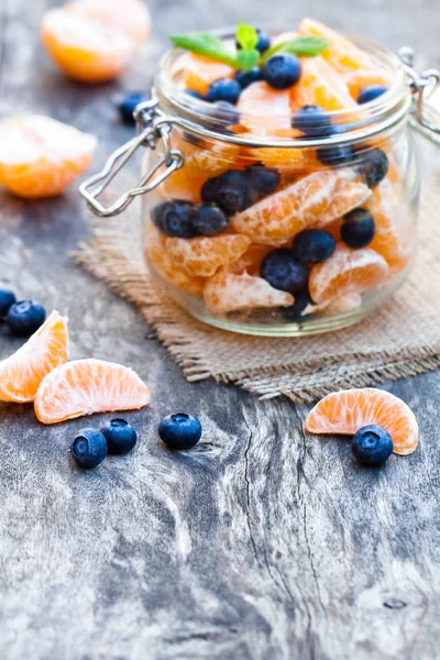 Peeled  tangerine or mandarin fruit and blueberry in glass jar o — Stock Photo, Image