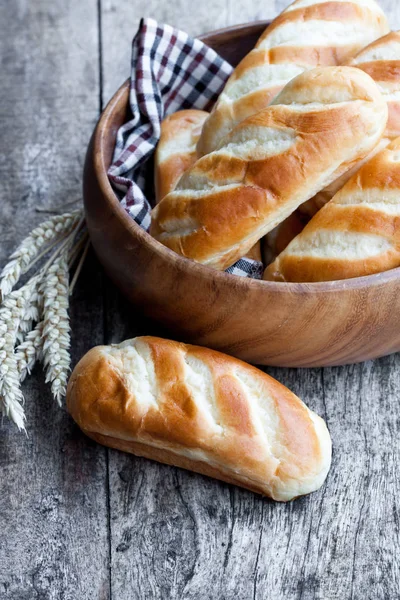 Мини хлеб в деревянной миске и колосья пшеницы на деревянном столе — стоковое фото