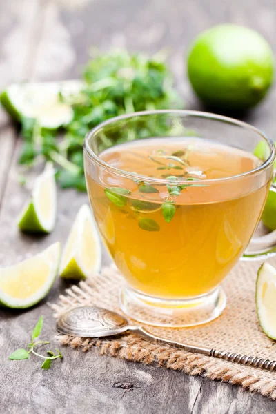 Té verde con tomillo y lima sobre fondo rústico de madera — Foto de Stock