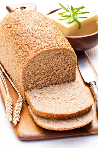 Sliced  slow-baked organic wholemeal bread with butter and rosem — Stock Photo, Image