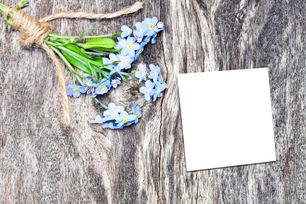 蓝色的花朵花束上的橡木棕色表与白色的表 — 图库照片