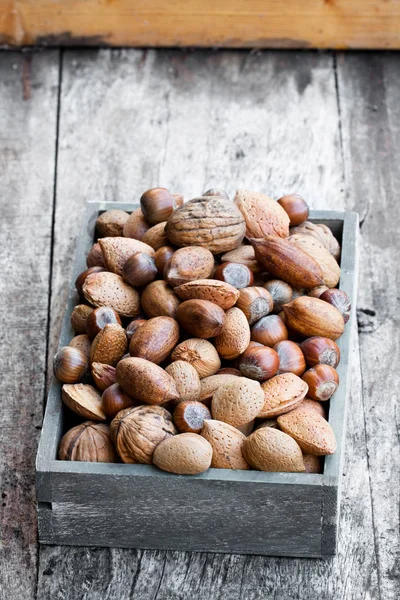 Various  nuts in wooden box on rustic table — Stock Photo, Image