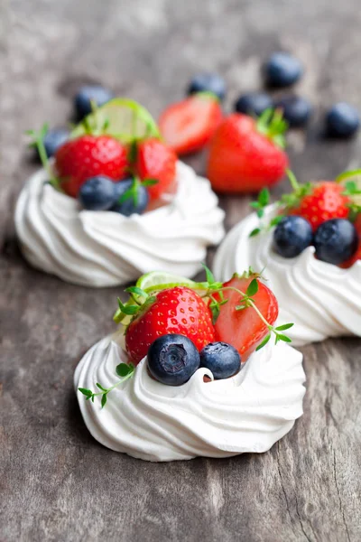 Mini  Pavlova meringue cakes with berries and lime on rustic woo — Stock Photo, Image