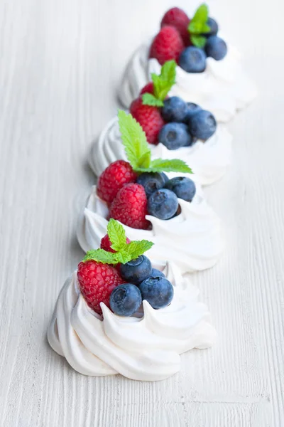 Mini  Pavlova meringue cakes with berries and mint on white wood — Stock Photo, Image