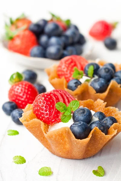 Brandy  snaps baskets with soft cream cheese and berries on whit — Stock Photo, Image
