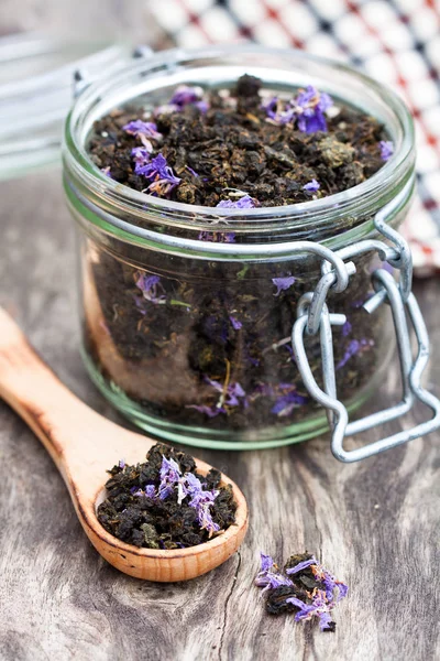 Black  tea with willow-herb in a glass jar on wooden background