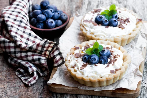 Deliciosas tartas con crema y arándanos frescos sobre mesa de madera —  Fotos de Stock