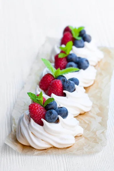 Mini Pavlova prăjituri cu meringue cu fructe de pădure și mentă pe lemn alb — Fotografie, imagine de stoc