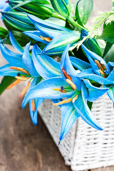 White  basket with blue lily flowers bouquet on rustic wooden ta — Stock Photo, Image