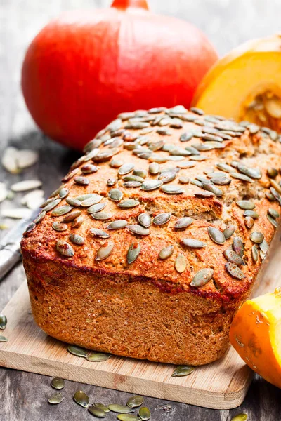 Pumpkin  bread loaf on wooden cutting board with seeds — Stock Photo, Image