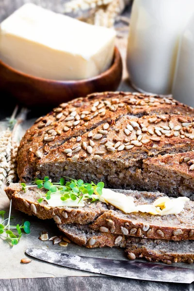 Sliced  homemade rye bread on baking paper and bottles of milk o — Stock Photo, Image