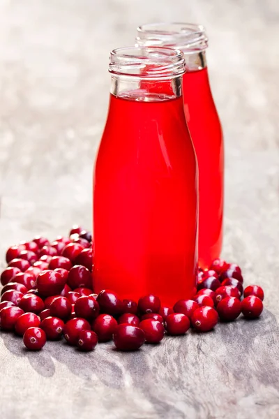 Suco de cranberry orgânico em garrafas com bagas em backg de madeira — Fotografia de Stock