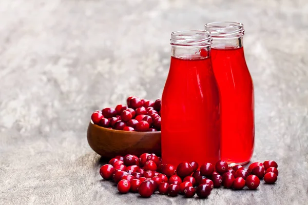 Органический клюквенный сок в бутылках с ягодами на деревянном бэкге — стоковое фото