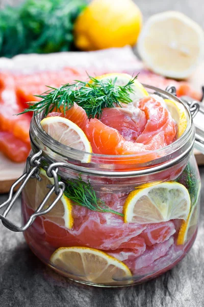 Salted  salmon with lemon in glass jar on wooden background