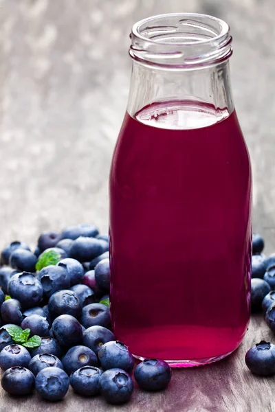Blueberry  juice in glass bottle on wooden table — Stock Photo, Image