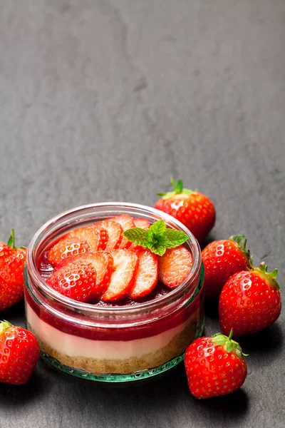 Mini  strawberry cheesecake in a glass pot on black stone backgr — Stock Photo, Image