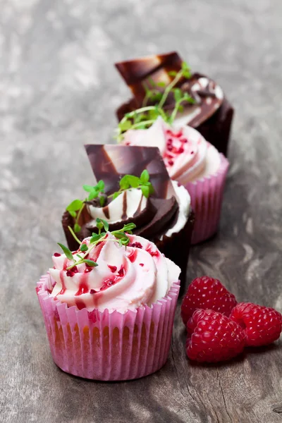 Cupcakes au chocolat avec framboises fraîches et crème sur t en bois — Photo