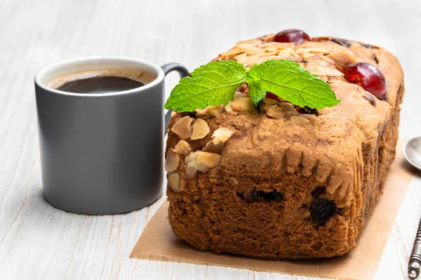 Mixed fruit loaf cake with cup of coffee on wooden table — Stock Photo, Image