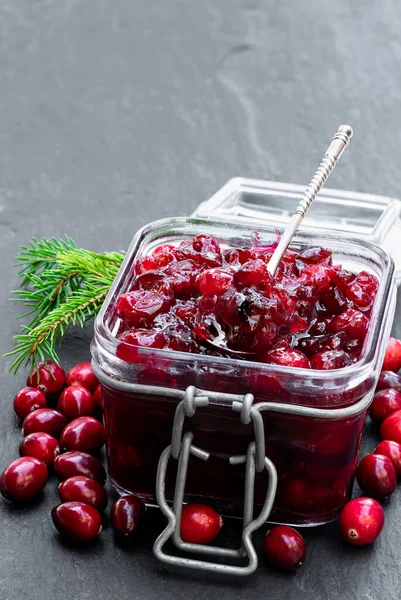 Fresh homemade cranberry sauce in glass jar on black stone table — Stock Photo, Image