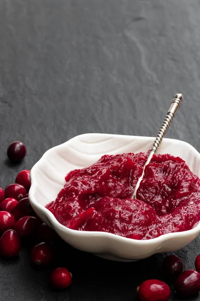 Fresh homemade cranberry sauce in white bowl on black stone table — Stock Photo, Image