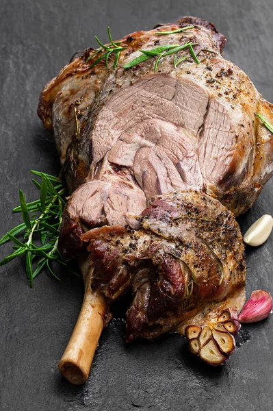 Whole roast lamb leg on black stone background — Stock Photo, Image