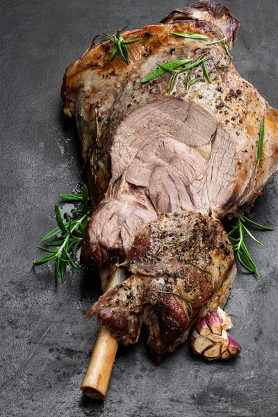 Whole roast lamb leg on black stone background — Stock Photo, Image
