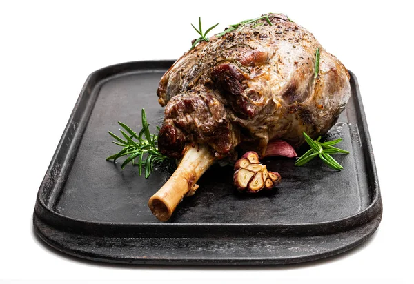 Kızarmış kuzu budu ızgara tepsisinde, beyaz tencerede. 