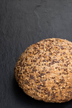 Siyah taş zemin üzerinde keten tohumu olan glütensiz çoklu tohum ekmeği 
