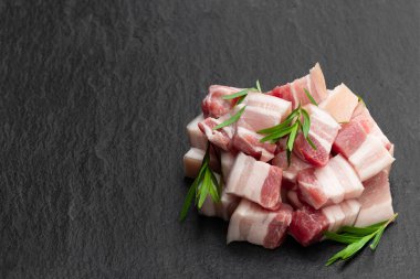 Siyah taş arka planda tarhun otlu domuz eti dilimleri. 